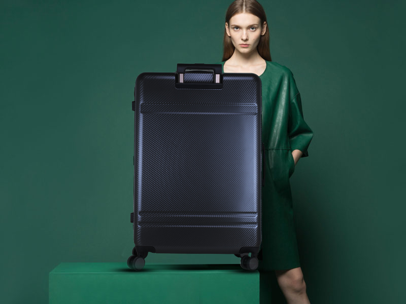 A girl standing behind the black trolley bag. A bag with 8 wheels.